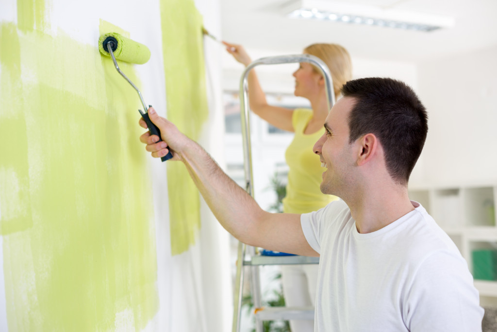 happy couple painting their homes wall